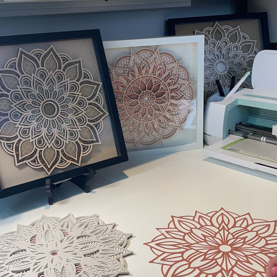 Watch as I assemble a 3d layered Mandala.  I'm using double sided 3m sticky tape and the fine point needle tool from Cricut. In the background are framed Mandalas in Shadow boxes.  Purchase your favorite 3d Layered Mandala Design at Home Stitchery Decor and follow along with the step-by-step tutorial.  3d Layered Mandala SVG instant download designs by Home Stitchery Decor