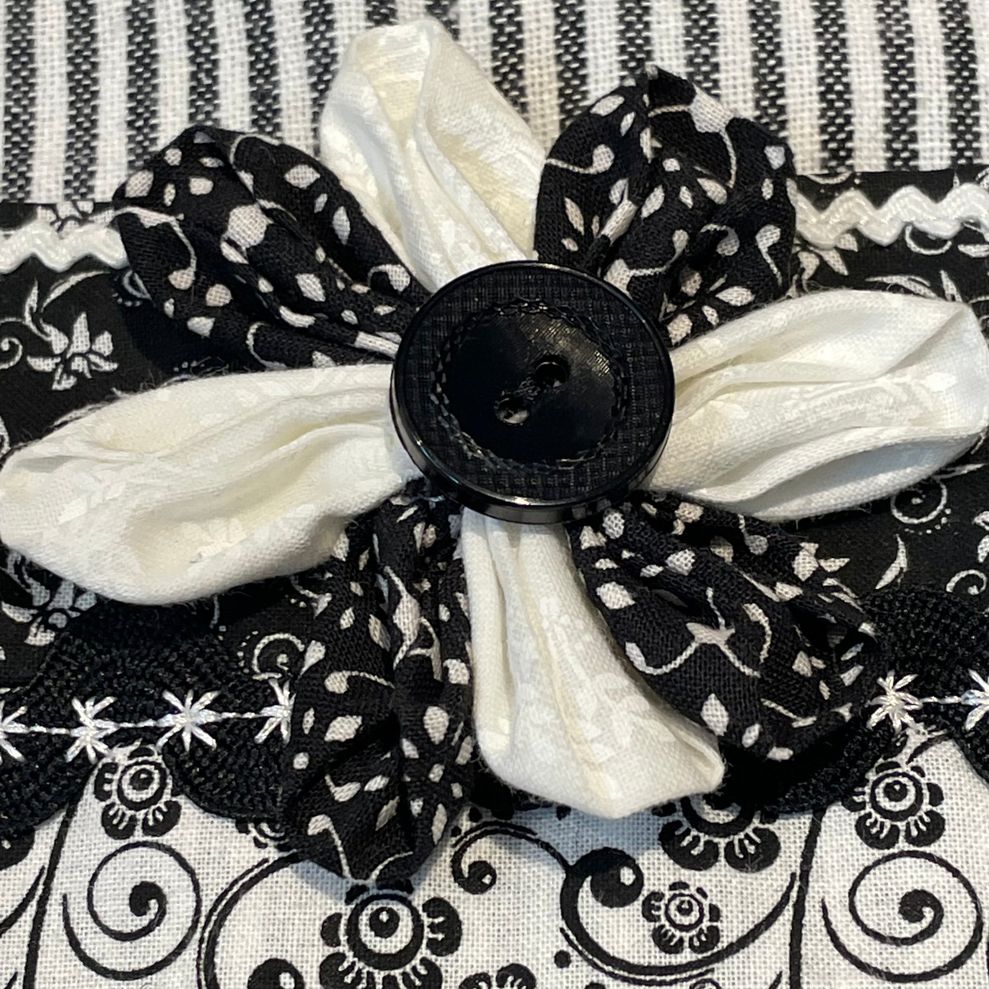 Black and white retro farmhouse tea towel. Featuring black and white striped toweling. Black and white floral quilting cotton accents with white and black ric rac, a handcrafted flower with button center and embroidery stitching. Part of a coordinating collection of farmhouse decor. Browse the entire collection. Then head over to the Home Stitchery Decor YouTube Channel for more Farmhouse DIY Decor Fun. See you there!