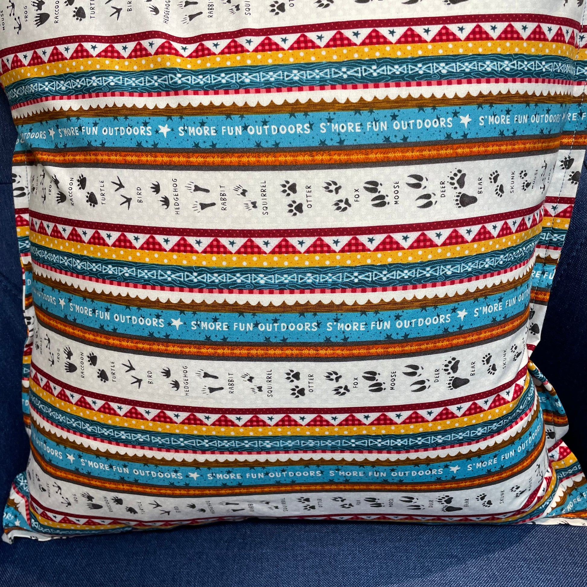 Camping Decorative Pillow for your RV, Camper Decor. Let's go camping with mix and match decor. Shop the collection and follow along on the Home Stitchery Decor YouTube Channel. Pillow in white, teal, red, yellow and black. Woodland tracks camping themed pillow.